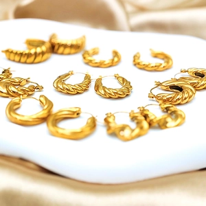 Detailed collection of gold croissant hoop earrings on champagne silk background