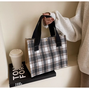 Detail of checkered canvas tote bag with jute trim and black handles on a desk