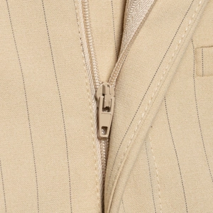 Detail eines eleganten beige gestreiften Sets aus Oberteil und Rock mit Reißverschluss