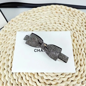 Detail of a black bow hair clip with shimmering grey rhinestones on a white card