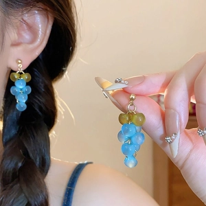 Détail de boucles d'oreilles grappe de raisin bleues en résine avec feuilles dorées