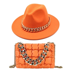 Vibrant orange fedora hat and matching quilted handbag with chunky gold chain details