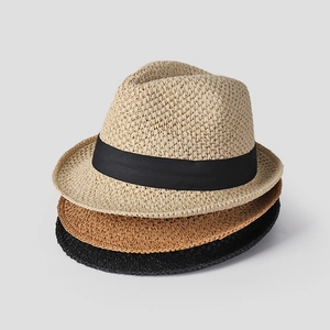 Close-up of stacked straw hats in beige, tan, and black with elegant ribbon details