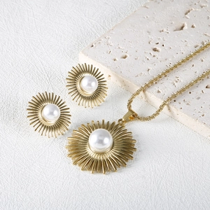 Golden sunburst jewelry set with pearl necklace and stud earrings on stone props