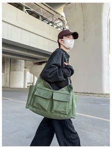 Outdoor shot of an army green canvas crossbody bag featuring large double front pockets
