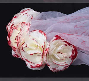 Detailed view of white blood-stained roses and mesh veil on a gothic Halloween headband