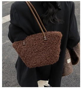 Détail d'un cabas en peluche marron montrant la texture laineuse et les anses en cuir