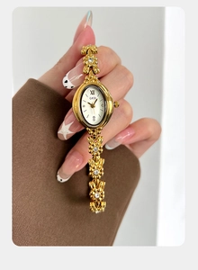 Close-up of vintage oval gold watch featuring camellia flower bracelet with inset diamonds
