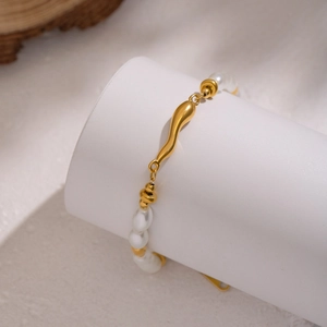 Baroque pearl and 18K gold plated stainless steel wave bracelet on jewelry display