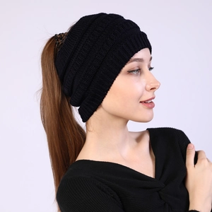 Detail view of the knitted ponytail opening on a black winter headband for long hair