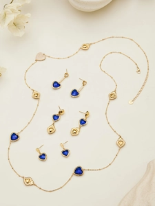 Detalle del conjunto de joyas doradas con piedras azules de corazón, collar y pendientes