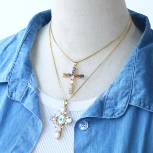 Detail of layered gold necklaces with colorful zircon evil eye cross pendants on model