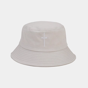 Close-up of white PEACE embroidery on beige cotton canvas bucket hat crown