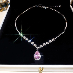 Macro shot of silver-tone necklace with pink teardrop pendant in velvet jewelry box