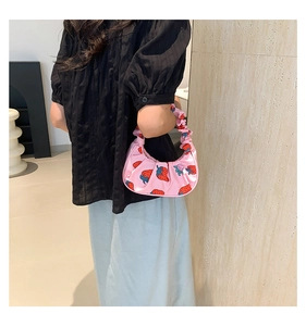 Dettaglio della borsa a spalla plissettata rosa con fragole indossata da modella