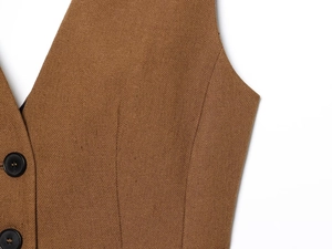 Close-up of brown linen blend vest fabric texture with black buttons and stitching