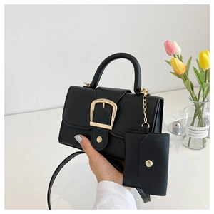 Detail of black pebbled leather crossbody bag with golden buckle and mini coin purse