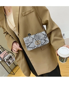 Fashionable snakeskin crossbody bag styled with a professional khaki suit and metal chain strap