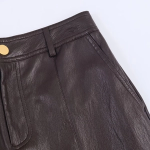 Detalle de los pantalones de cuero marrón oscuro con botones dorados y costuras
