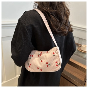 Detail of corduroy shoulder bag featuring embroidered cherries on a beige fabric