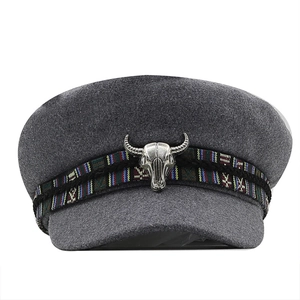 Grey wool newsboy flat cap featuring a bohemian woven band and silver bull skull accent