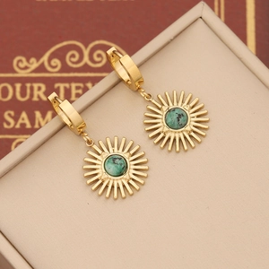 Macro detail of gold sunburst drop earrings featuring an inlaid green natural stone