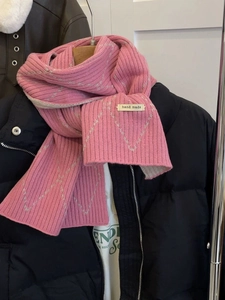 Macro detail of pink knit scarf with grey diamond pattern and hand made label