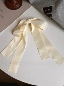 Détail d'une pince à cheveux nœud en satin blanc crème avec longs rubans élégants