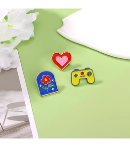 Flat lay of colorful enamel pins featuring heart, arch, and game controller designs