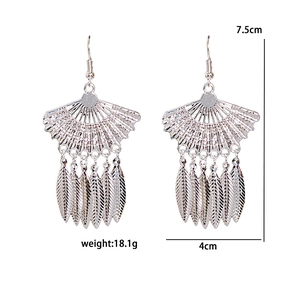 Detailed view of silver ethnic fan earrings with tassel and peacock leaf patterns
