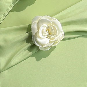 Detail of a 3D cream white fabric rose with soft silk petals on a light green swimsuit