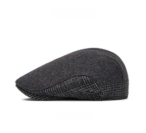 Detail view of the gray wool flat cap showing the side plaid pattern and metal logo