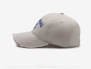 Detail of vintage beige cotton baseball cap with blue 3D embroidery and distressed edges