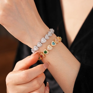Detailed view of heart-shaped zircon bracelets in gold and silver on a model wrist