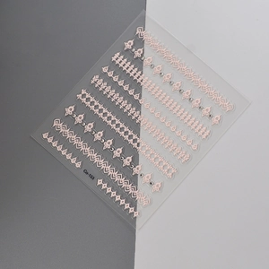 Macro detail of 3D embossed pink lace nail art stickers with small rhinestones