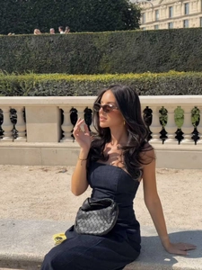 Ripresa esterna di un abito lungo senza spalline in denim nero con borsa intrecciata
