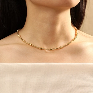 Close-up of elegant gold beaded necklace with pearls on a model neck with white top