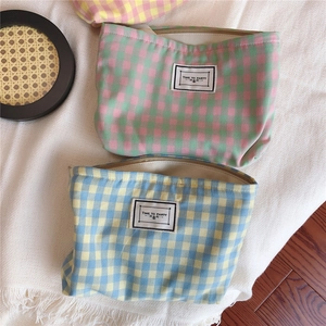 Flat lay of plaid cotton cosmetic bags with Time to Party tags on a textured rug