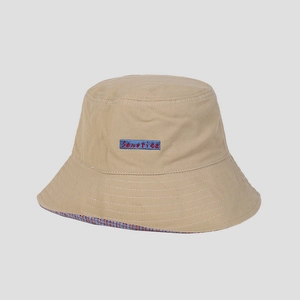 Close-up of khaki cotton bucket hat with blue embroidered patch and plaid brim detail
