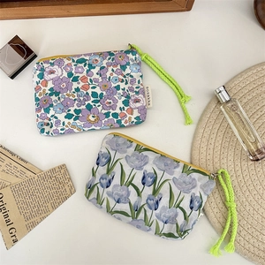 Macro view of two floral cosmetic pouches with vibrant green rope handles on desk