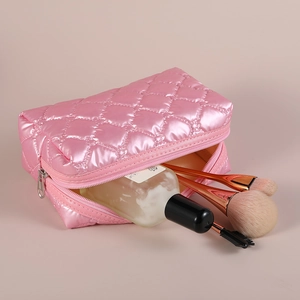 Pink quilted down makeup bag with zipper and cosmetics accessories shown in studio light
