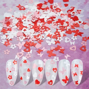Detail of red and white heart butterfly nail sequins on artificial nails and scattered
