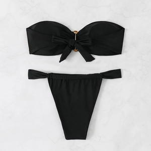 Detailed flat lay of black bandeau bikini set with bow tie and tortoiseshell rings