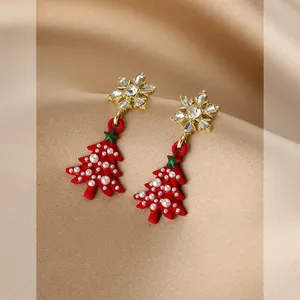 Close-up of snowflake and Christmas tree earrings with pearls on champagne satin silk