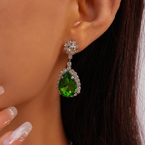 Gros plan de boucles d'oreilles émeraude verte en forme de poire et sertissage diamant