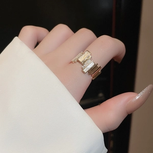 Detail of a geometric gold-plated ring with white zircon and shell-like inlay on fingers