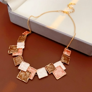 Detail of geometric enamel square pendant necklace with brown and cream tiles in gold
