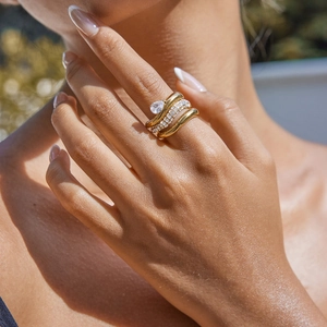 Close-up of gold titanium steel rings with teardrop cubic zirconia on female hand