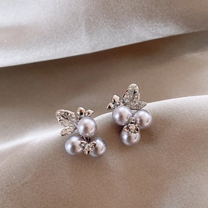 Macro shot of gray pearl cluster earrings with zircon inlaid metal leaves on silk