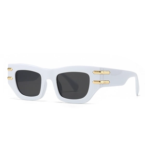 Lunettes de soleil œil-de-chat blanches avec monture épaisse et détails dorés sur verres noirs